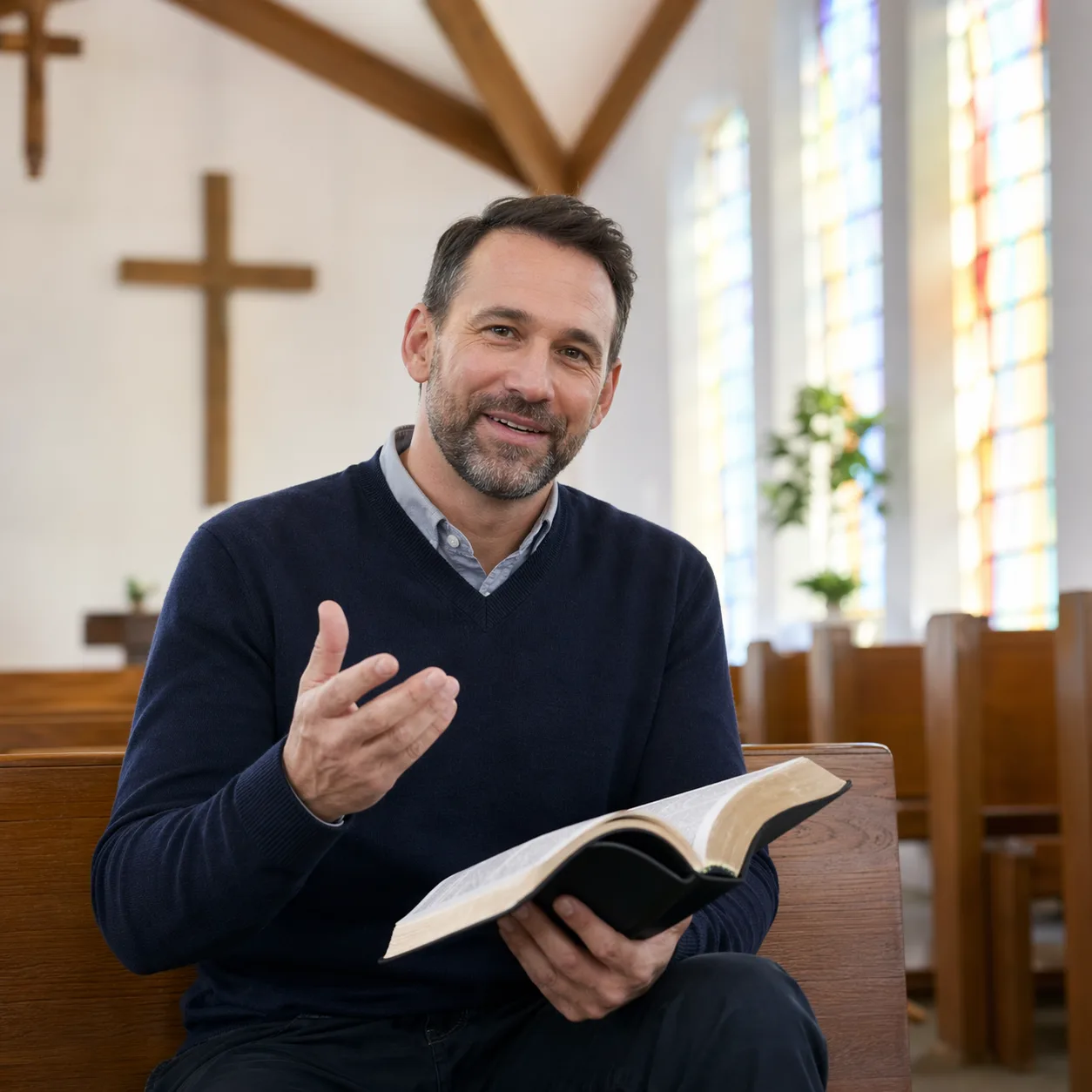 Pastor drafting a church devotional book, holding an open bible on a wooden pew with two wooden crosses and sunlit windows behind him