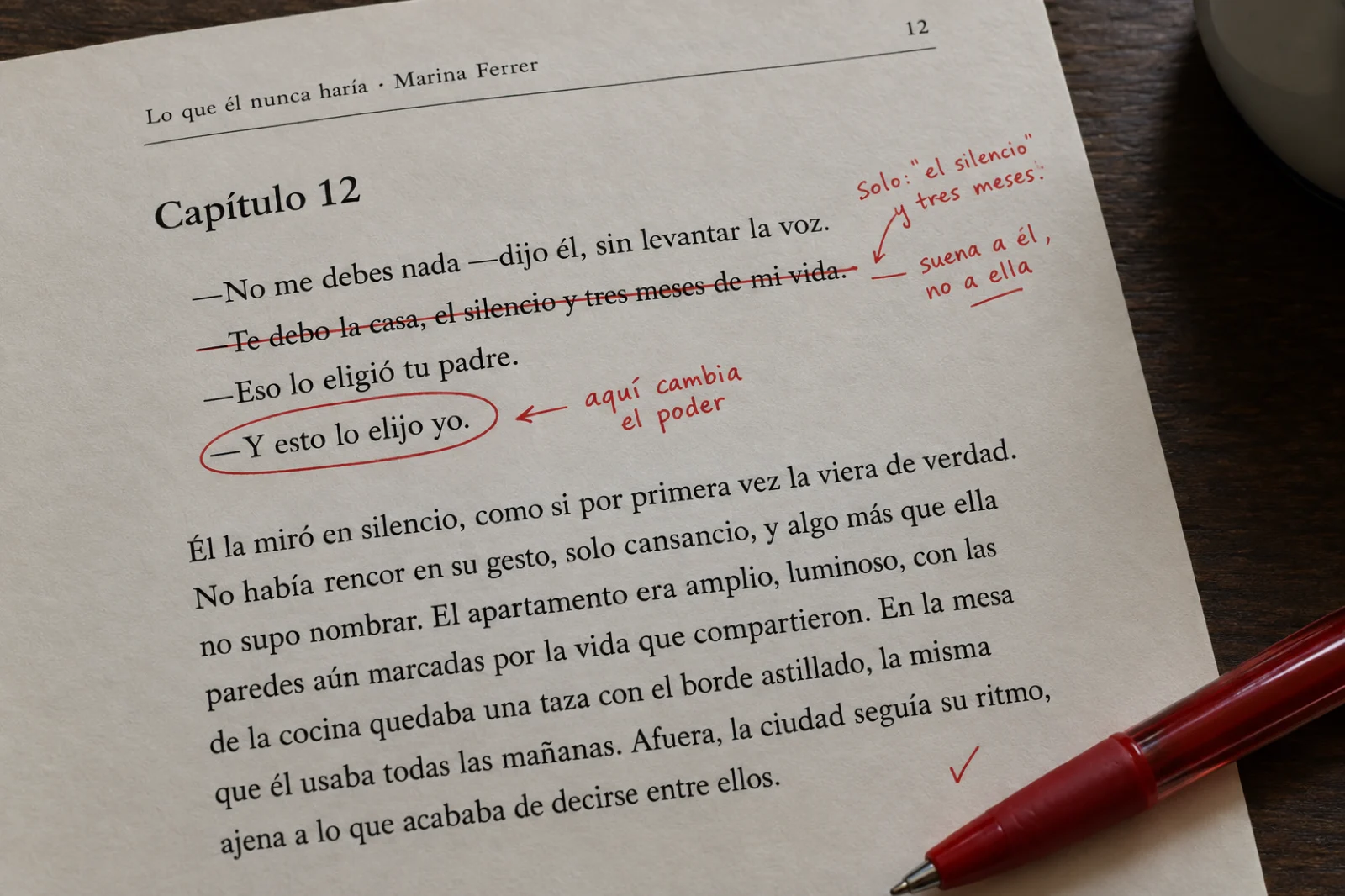 Primer plano de una página impresa de manuscrito, 'Capítulo 12', con diálogo en español con raya y anotaciones a bolígrafo rojo: una línea de ella tachada y reescrita, 'suena a él, no a ella' en el margen, y un círculo sobre 'aquí cambia el poder' junto a una réplica