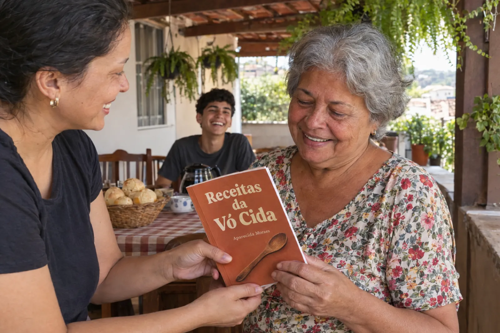 Almoço de domingo na varanda de uma casa em Belo Horizonte: uma mulher de uns trinta e cinco anos entrega à mãe, de cabelos grisalhos e blusa florida, um livro impresso de capa terracota chamado Receitas da Vó Cida, com o nome Aparecida Moraes embaixo do título; atrás delas, uma mesa com toalha xadrez, cesta de pão de queijo e bule de café, e um neto rindo ao fundo.